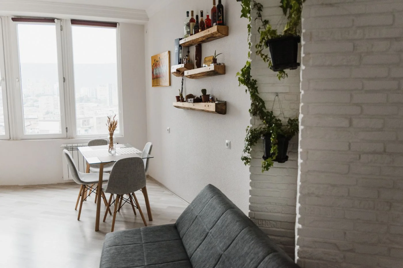 Dining table and grey sofa sharing a bright apartment living space