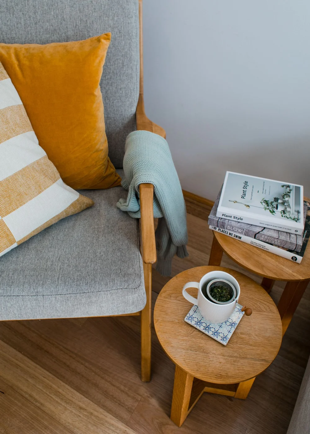 Side tables holding books and a cup beside an armchair