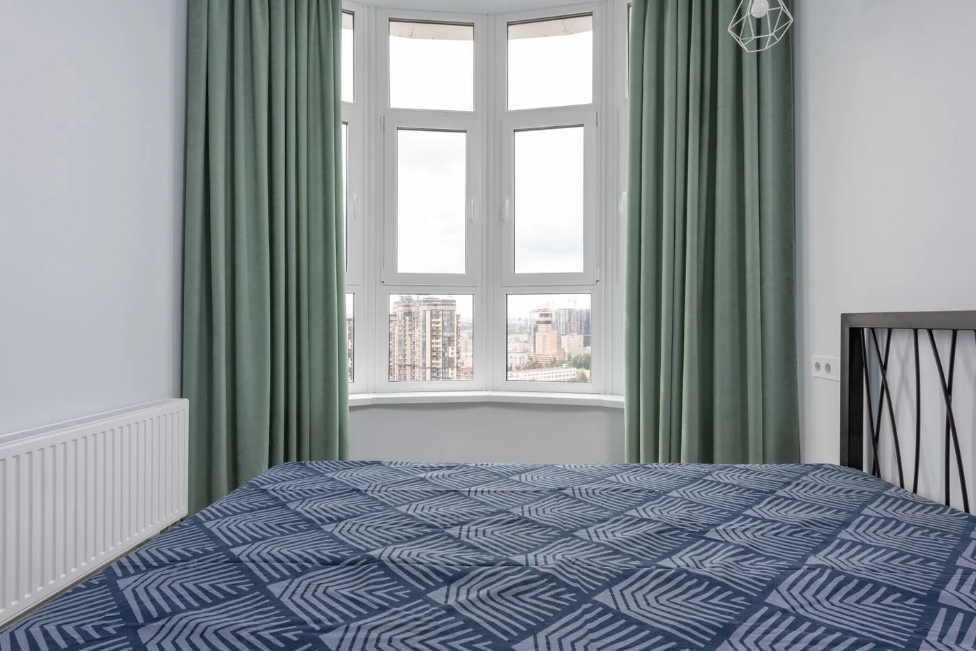 Double bed with a blue bedspread beside a window