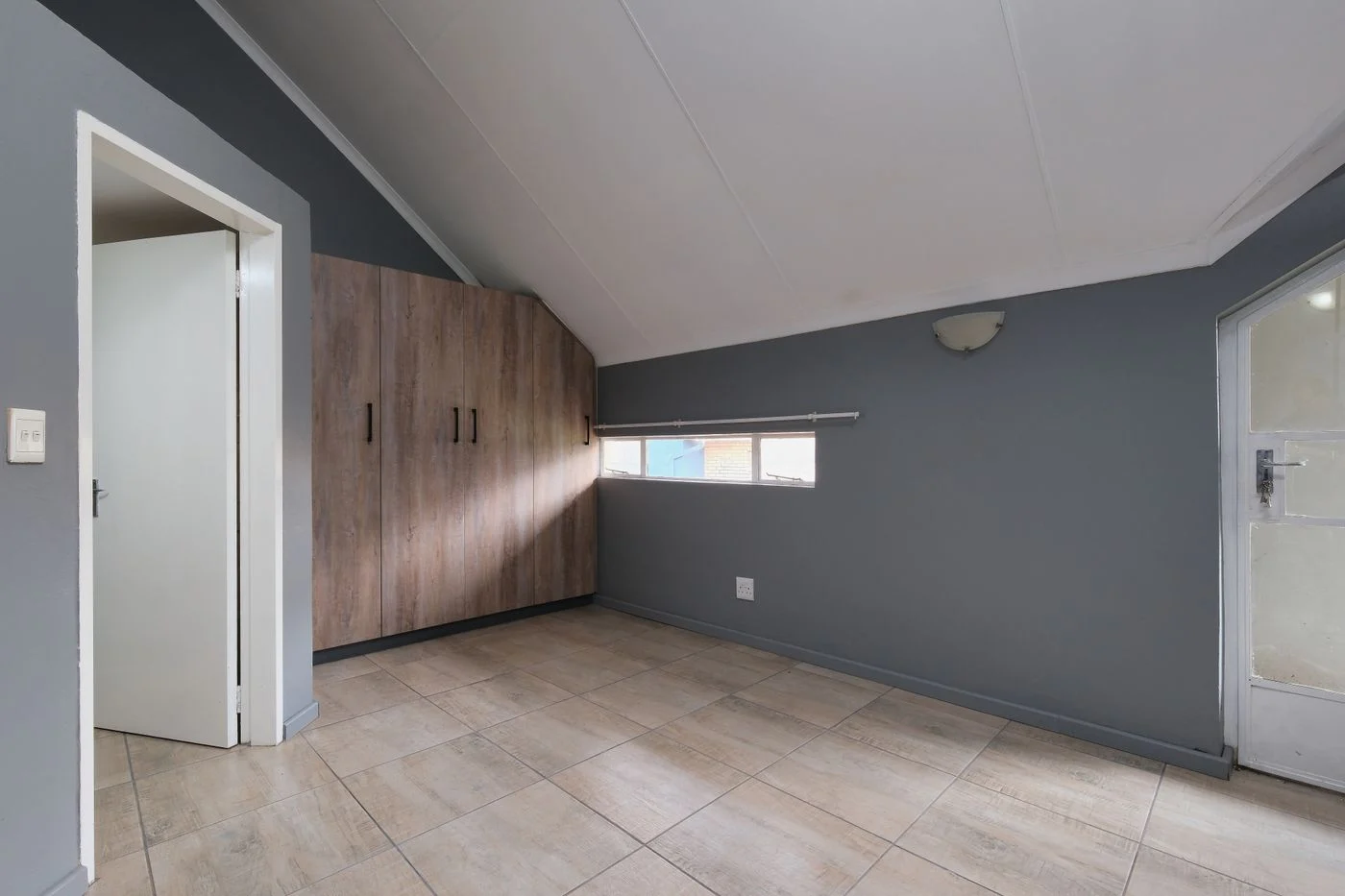 Built-in wooden wardrobe beneath a sloping ceiling