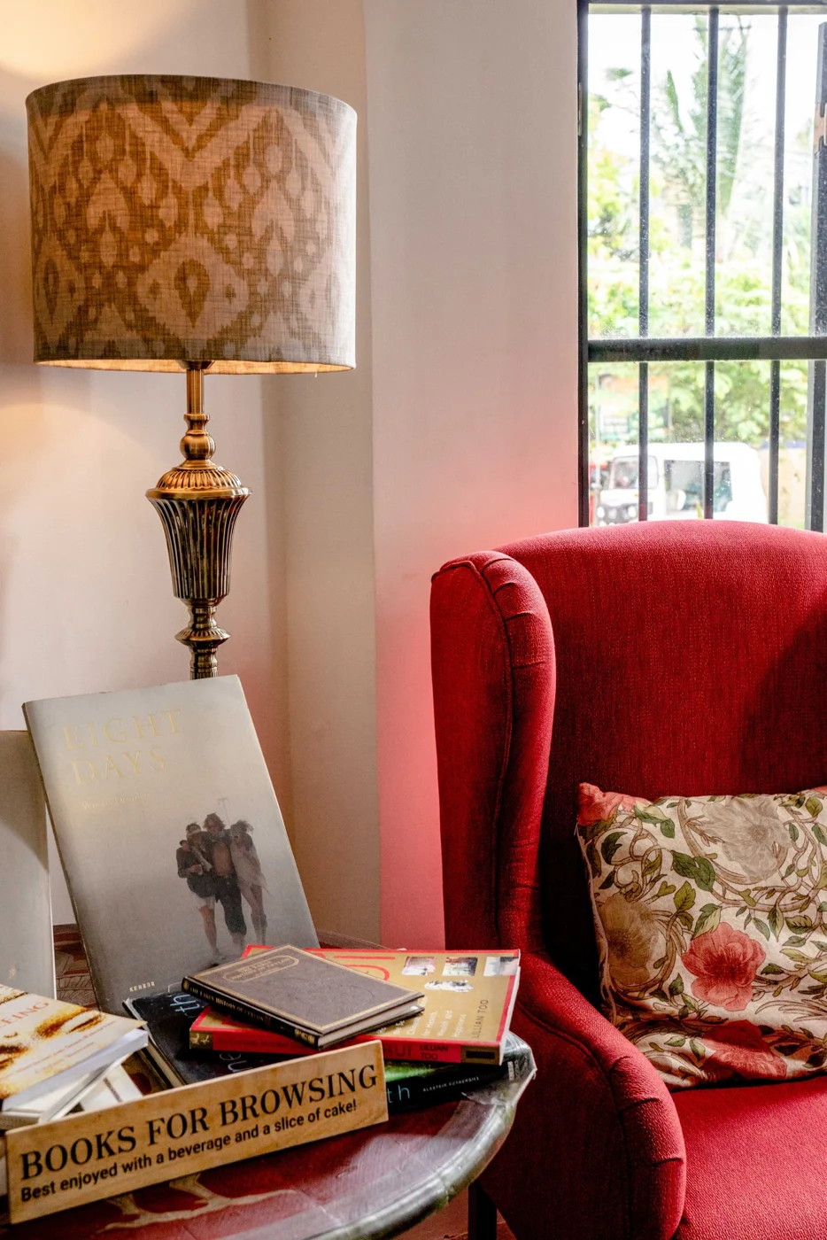 Red reading armchair beside a floor lamp and books