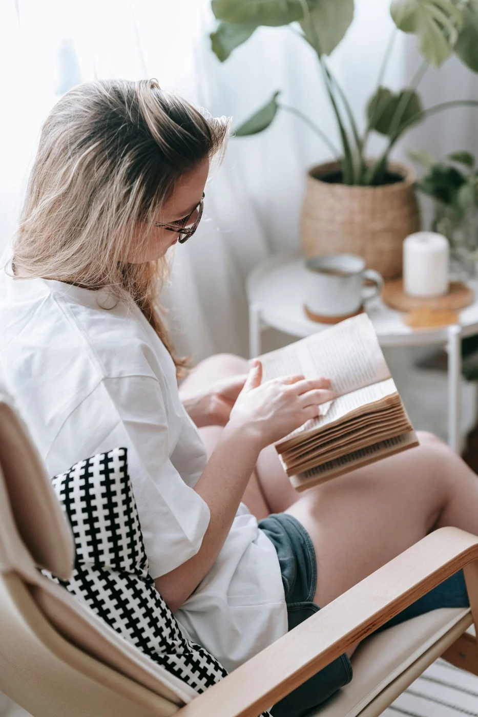 Woman reading in an armchair beside houseplants