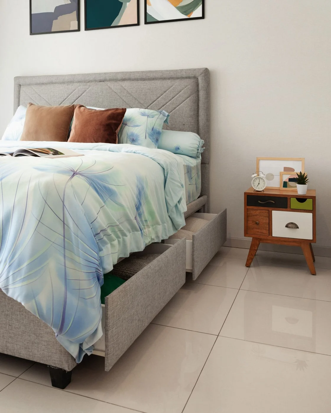 Grey upholstered bed with an open storage drawer below the mattress