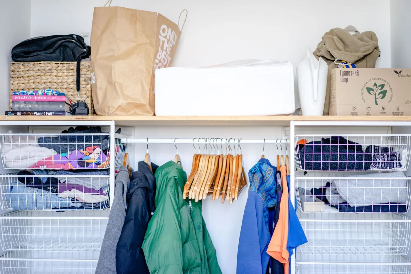 Open wardrobe with hanging clothes and baskets