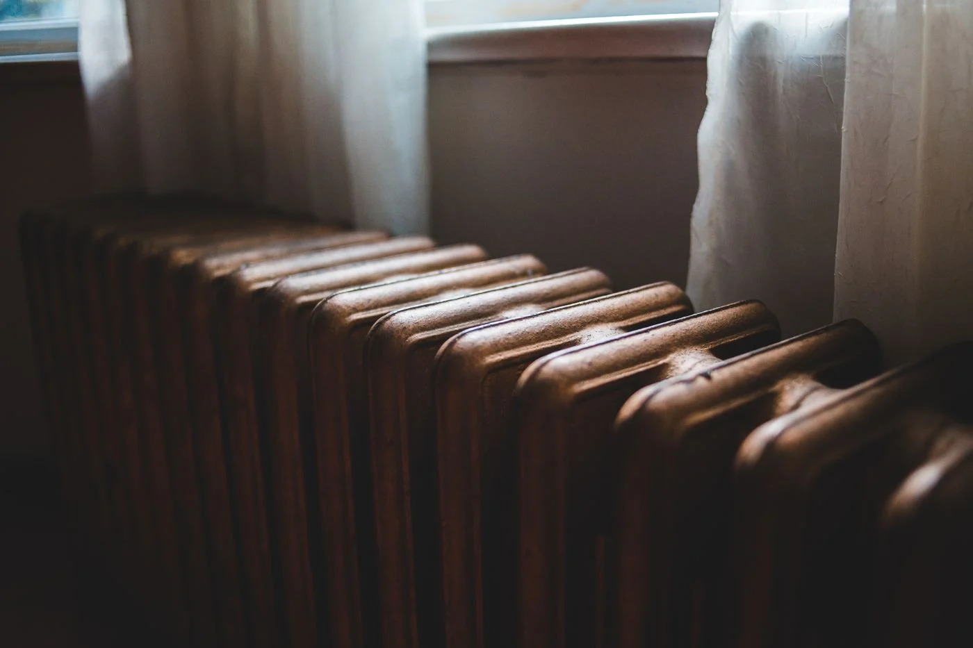 Radiator beneath a window beside curtains