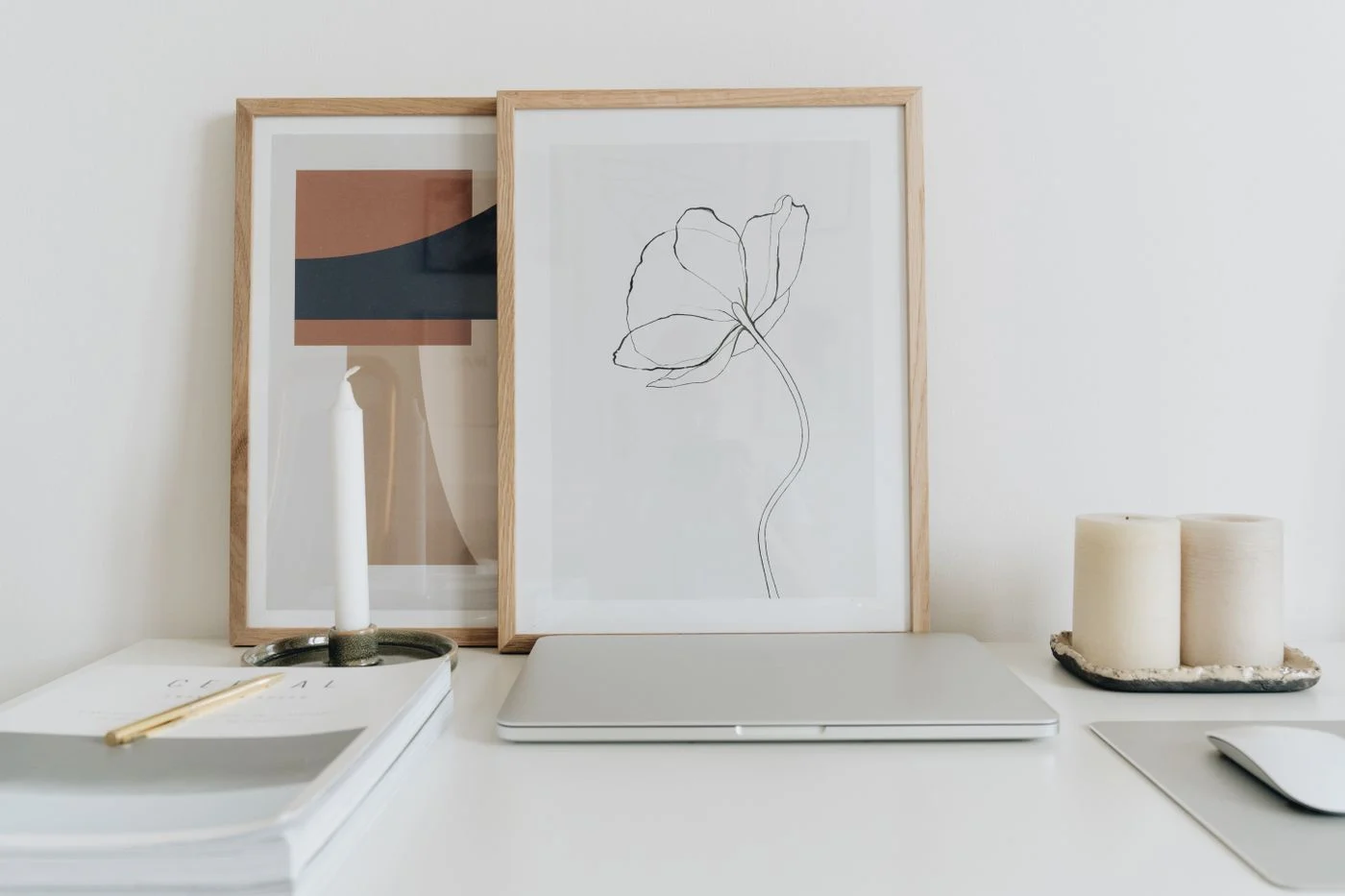 Closed laptop and framed pictures on a clear white home-office desk