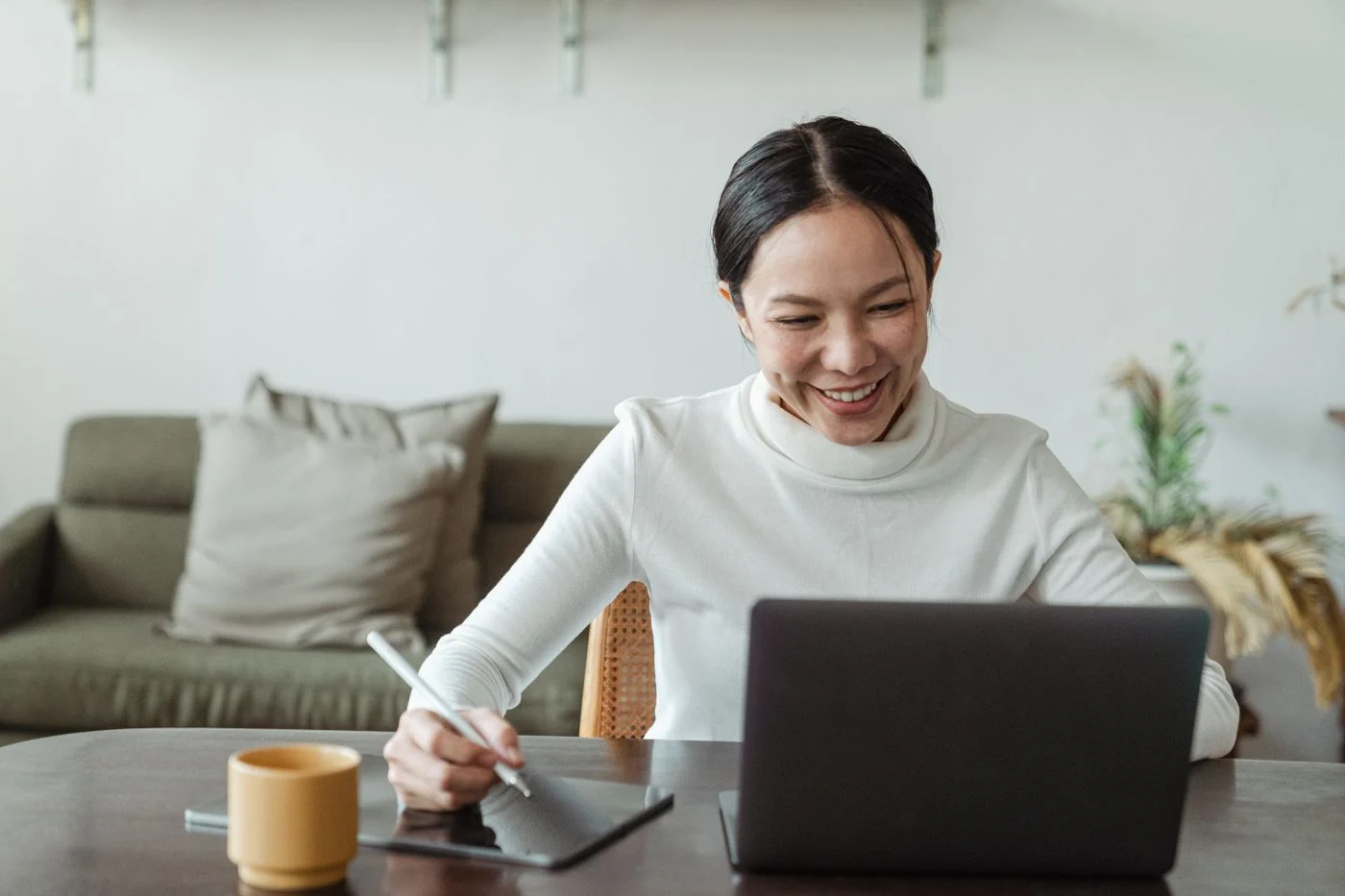 Woman taking notes during a laptop video call at home