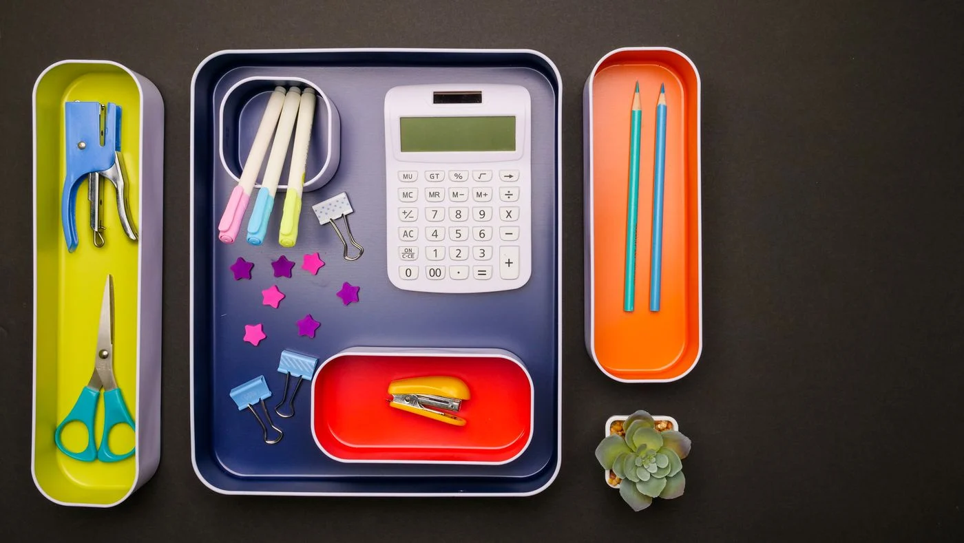 Pens and desk supplies sorted on small trays
