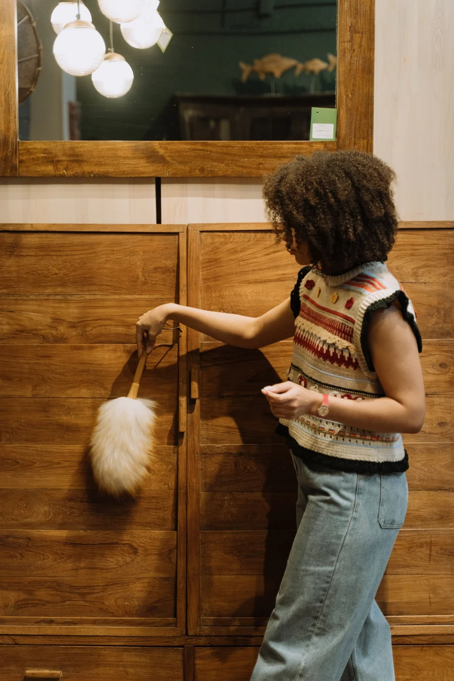 Dusting a wooden cabinet with a soft duster